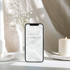 May include: A smartphone with a marble-patterned screen displaying the text "NUR MIT EUCH an unserer Seite" and a heart symbol. The phone is on a white surface, next to a lit candle and a vase of white flowers.