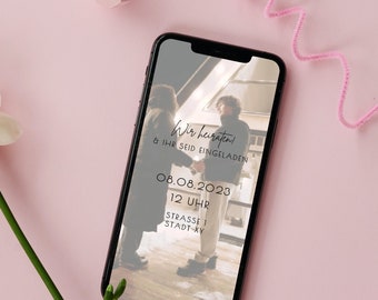 May include: A smartphone screen displaying a wedding invitation with a photo of a couple in the background. The text reads "Wir heiraten! & Ihr seid eingeladen" and includes the date "08.08.2023", time "12 Uhr", and location "Strasse 1 Stadt-XY".