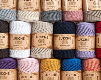 Op de afbeelding: Assortiment van 10 spoelen van 4 mm enkelvoudige macramé-koord in verschillende kleuren, waaronder naturel, grijs, roze, wit, zwart, paars, rood, geel, blauw en perzik. Elke spoel heeft een bruin etiket met de tekst "LUKCHE 4 mm Single Strand Macrame Cord".