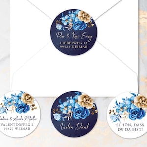 Könnte beinhalten: Runde marineblaue Aufkleber mit floralen Designs in Blau und Gold. Die Aufkleber enthalten Text, darunter Namen und Adressen, sowie Sätze wie "Vielen Dank" und "Schön, dass du da bist!" auf einem weißen Umschlag.