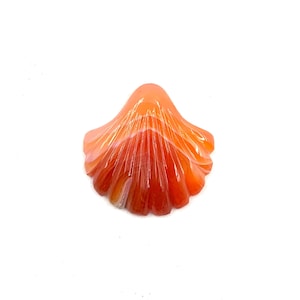 May include: A carved orange agate shell with white and orange striations. The shell is shaped like a flower with multiple layers of petals.