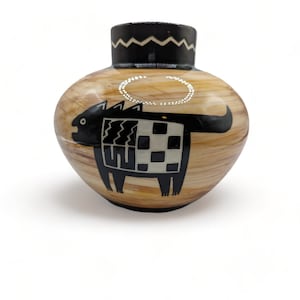 Könnte beinhalten: Eine braune Keramikvase mit einem stilisierten Tiermotiv in Schwarz und Weiß. Die Vase hat einen runden Körper und einen schwarzen Rand mit einem weißen Zickzackmuster.