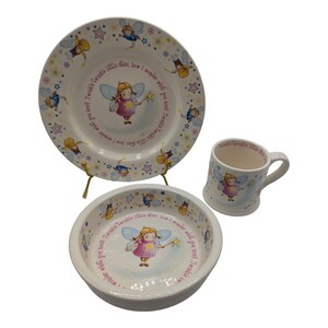 Puede incluir: Un juego de vajilla de cerámica blanca para niños con un diseño de hada y estrella. El juego incluye un plato, un tazón y una taza. El plato y el tazón tienen el texto "Twinkle Twinkle little star, how I wonder what you are?" impreso en ellos.
