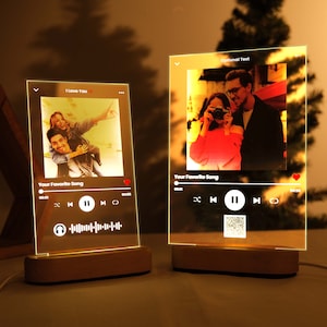 May include: Two illuminated glass frames with wooden bases, each displaying a photo and a music player interface. The top frame has the text "I Love You" and the bottom frame has the text "Optional Text".