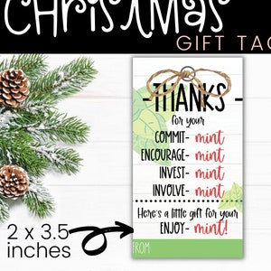 May include: A white gift tag with green and white foliage designs. The tag has black text that reads "Thanks for your COMMIT-mint ENCOURAGE-mint INVEST-mint INVOLVE-mint Here's a little gift for your ENJOY-mint!" and "FROM:". The tag is 2 inches by 3.5 inches.