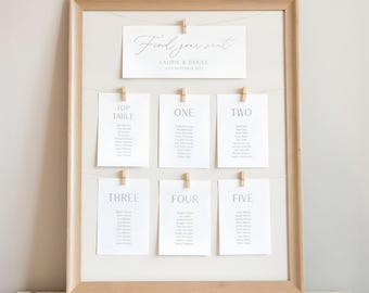 May include: A wooden frame with a white background holds a wedding seating chart. The chart is made up of cards with the names of guests and their assigned tables. The top card reads "Find your seat" with the couple's names and wedding date. The other cards are labeled "Top Table", "One", "Two", "Three", "Four", and "Five".