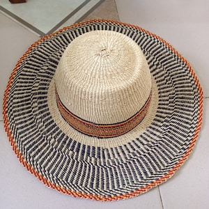 以下が含まれることがあります： 黒と白のストライプ模様と、赤と黄色のトリムがついた、つば広の麦わら帽子です。