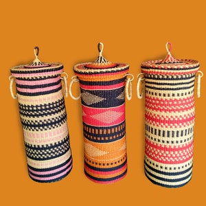 May include: Three woven storage baskets with lids. The baskets are cylindrical and have a black, white, orange, and pink striped pattern.