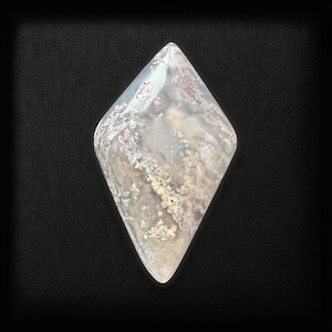 Può includere: Una pietra di agata trasparente a forma di diamante con inclusiones bianche e viola. La pietra è traslucida e ha una superficie liscia e lucida.