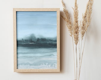 May include: A framed watercolor painting of a blue and gray landscape with a wooden frame. A white vase with a textured surface holds dried pampas grass.