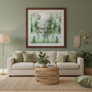 May include: A living room with a framed art print above a cream sofa. The artwork depicts a watercolour forest scene with the text "Nature is not a place, it is a feeling." Decorative cushions and a woven coffee table complete the scene, creating a cosy atmosphere.