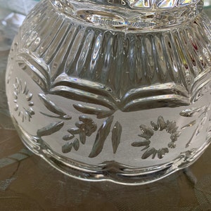 Peut inclure: Un bol en verre transparent avec un motif grav&eacute; d&eacute;coratif de fleurs et de feuilles. Le bol a un bord festonn&eacute; et une surface textur&eacute;e.