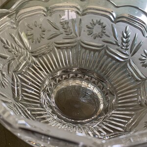 Peut inclure: Un bol en verre transparent avec un bord festonn&eacute; et des motifs grav&eacute;s complexes. Le bol a un centre sur&eacute;lev&eacute; et un motif d&eacute;coratif de fleurs et de feuilles.
