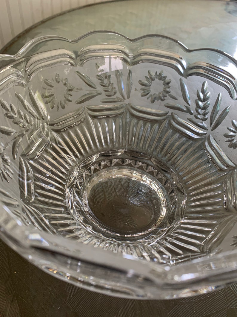 Peut inclure: Un bol en verre transparent avec un bord festonn&eacute; et des motifs grav&eacute;s complexes. Le bol a un centre sur&eacute;lev&eacute; et un motif d&eacute;coratif de fleurs et de feuilles.