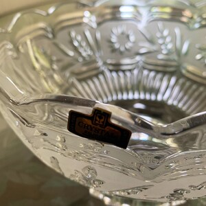 Peut inclure: Un bol en verre transparent avec un bord festonn&eacute; et des motifs floraux grav&eacute;s complexes. Le bol porte une &eacute;tiquette dor&eacute;e sur laquelle est inscrit "Crystal Silver".