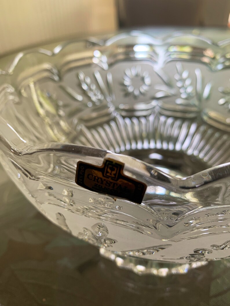 Peut inclure: Un bol en verre transparent avec un bord festonn&eacute; et des motifs floraux grav&eacute;s complexes. Le bol porte une &eacute;tiquette dor&eacute;e sur laquelle est inscrit "Crystal Silver".