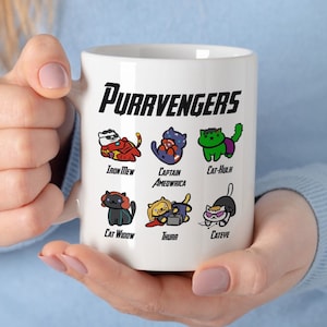 May include: White ceramic mug featuring a black and white illustration of cats dressed as the Avengers. The text "Purrvengers" is at the top of the mug. The cats are labelled "Iron Mew", "Captain Ameowrica", "Cat-Hulk", "Cat Widow", "Thurr", and "Cateye".