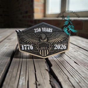 May include: A wooden plaque with a patriotic design. The plaque features an eagle with outstretched wings, the text "250 YEARS", "1776", and "2026". The words "MADE IN AMERICA" are also visible. The plaque is set against a rustic wooden background.