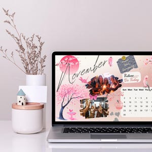 May include: A laptop computer with a pink and white floral design on the screen. The screen shows a calendar for November with the words "Never Stop Dreaming" and "Future Do Today" written on it. There are also photos of people in the background.