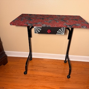 Red Roses and Spider Webs on a Black Rolling Table with drawer