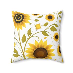 May include: White cushion with a sunflower design. The cushion features yellow sunflowers with brown centres and green leaves on a white background.