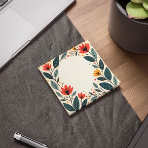Può includere: Un blocco note floreale con sfondo bianco e un cerchio al centro. Il bordo del cerchio è composto da foglie verdi, fiori rossi e arancioni e punti gialli.