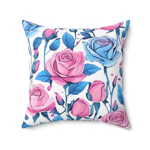 May include: A white cushion with a floral pattern featuring pink and blue roses with green leaves.