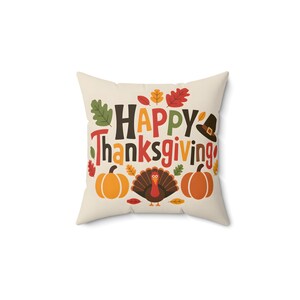 May include: A cream-coloured throw pillow with a Thanksgiving-themed design. The pillow features the text "Happy Thanksgiving" in colourful letters, surrounded by autumn leaves, pumpkins, and a turkey.