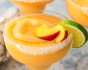 May include: Three frozen peach margaritas in margarita glasses with a sugared rim. Each glass is garnished with a slice of peach and a lime wedge.