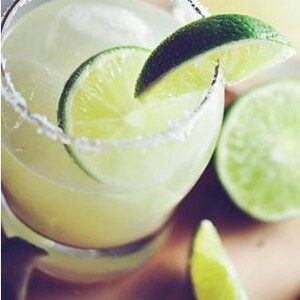 May include: A glass of margarita with a salted rim, lime wedges, and ice. The drink is in a clear glass and is garnished with a lime wedge.