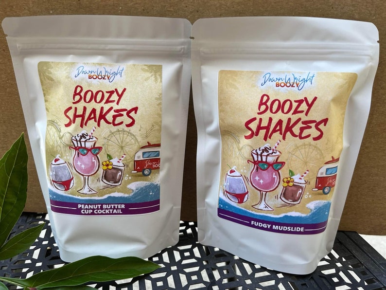May include: Two white pouches with colorful labels. The labels say "Dream Right Boozy" and "Boozy Shakes". One pouch says "Peanut Butter Cup Cocktail" and the other says "Fudgy Mudslide".
