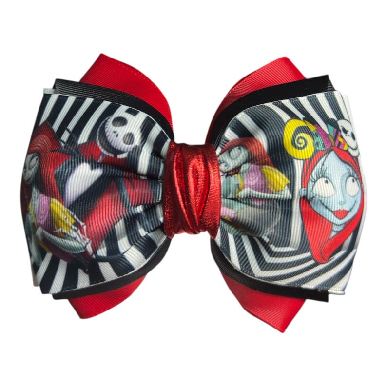 May include: A large, decorative hair bow featuring characters from The Nightmare Before Christmas. The bow has a red center and red accents, with a black and white striped pattern. The characters Jack Skellington and Sally are prominently displayed.