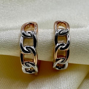 May include: A pair of gold and silver hoop earrings with a chain link design.