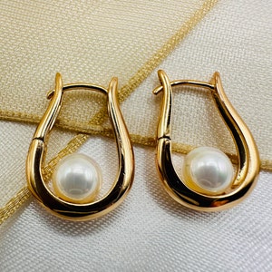 May include: A pair of gold hoop earrings with a white pearl in each hoop.