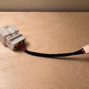 May include: A white electrical connector with a black wire and a white connector on the other end. The connector has red and black wires coming out of it.