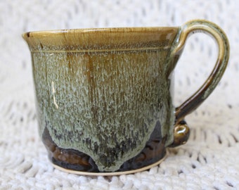 Ceramic mug, hand-thrown in tones of mottled olive-brown and dark brown. Unique and sturdy hand-pulled handle. Signed and dated.