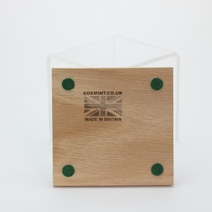 Puede incluir: La parte inferior de una caja de madera con cuatro almohadillas de fieltro verde. La caja tiene el texto "boxmint.co.uk" y "Made in Britain" impreso en ella.