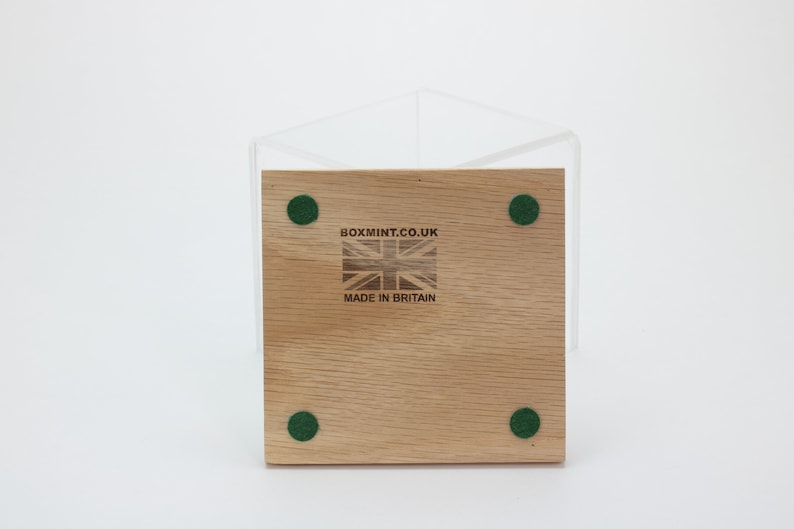 Puede incluir: La parte inferior de una caja de madera con cuatro almohadillas de fieltro verde. La caja tiene el texto "boxmint.co.uk" y "Made in Britain" impreso en ella.