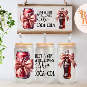 May include: Three frosted glass tumblers with lids and straws. Each tumbler features a different design: a can of Coca-Cola with a pink bow, a bottle of Coca-Cola with a pink bow, and the text "Just a girl who loves her Coca-Cola".