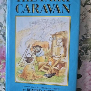 May include: A vintage hardcover book titled "THE FAIRY CARAVAN" by Beatrix Potter. The cover is light blue with gold lettering and a colorful illustration of animal characters around a caravan. The book is an original and authorized edition.