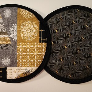 May include: Two round fabric coasters. One coaster features a Christmas tree design with snowflakes, gold, and gray patches. The other coaster has a black and gold geometric pattern. Both have a black border.