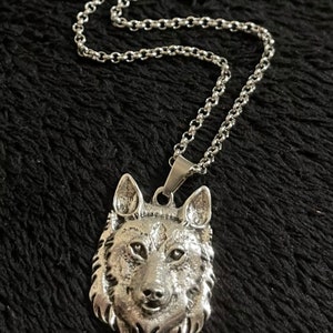 Könnte beinhalten: Eine silberne Kettenkette mit einem Wolfskopf-Anhänger. Der Anhänger ist detailliert und hat ein realistisches Aussehen.