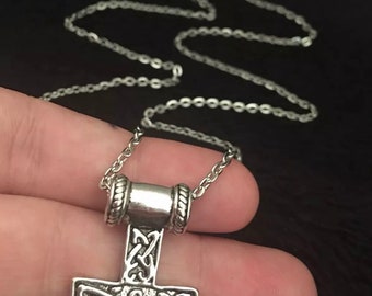 May include: A silver chain necklace with a silver Mjolnir pendant. The pendant is detailed with intricate knotwork.