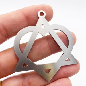 May include: A silver-colored pendant featuring a Star of David design with a heart and triangle incorporated into the design. The pendant has a small hole at the top for hanging. The metal has a brushed finish.