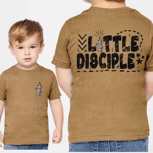 Könnte beinhalten: Zwei braune Kinder-T-Shirts. Die Vorderseite des ersten Shirts hat ein kleines kariertes Flaggen-Design. Auf der Rückseite des zweiten Shirts stehen die Worte "LITTLE DISCIPLE" in Schwarz, mit karierten Flaggen- und Sternakzenten.