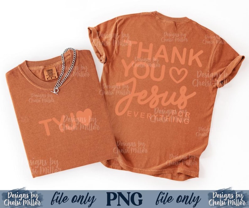 May include: Two rust-colored t-shirts with the text "THANK YOU JESUS" and "TY" printed on them. A silver chain necklace with a toggle clasp is draped over one shirt. The shirts are on a white background.