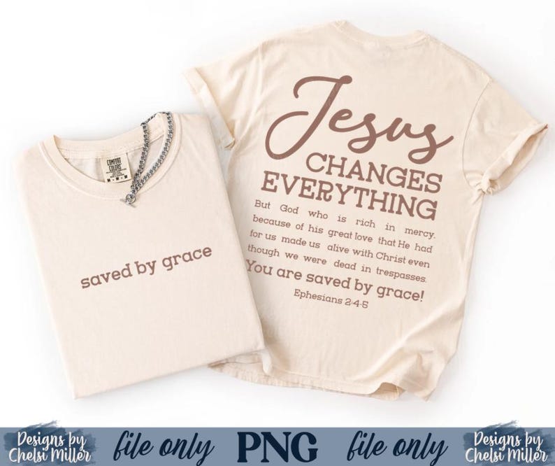 K&ouml;nnte beinhalten: Zwei cremefarbene T-Shirts. Eines ist gefaltet, mit "saved by grace" in Braun gedruckt. Das andere Shirt hat "Jesus CHANGES EVERYTHING" und einen Bibelvers auf der R&uuml;ckseite. Eine silberne Halskette befindet sich auf dem gefalteten Shirt.