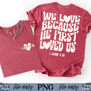May include: Two maroon t-shirts with white text and graphics. One shirt has a heart graphic with "1 JOHN 4:19" and a silver chain necklace. The other shirt has the text "WE LOVE BECAUSE HE FIRST LOVED US" and "1 JOHN 4:19".