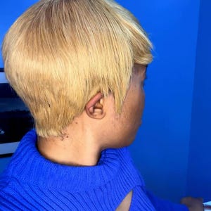 Puede incluir: Una persona con pelo rubio corto y un suéter azul. El pelo está peinado en un corte corto y en capas. El suéter es de un azul vibrante con un detalle de corte en el escote.