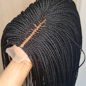 May include: Black braided wig with a lace front. The wig is styled in small, thin braids that are about 10 inches long.